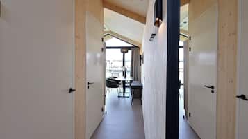Un pasillo con paredes y puertas de madera que conduce a un comedor con mesa y sillas.