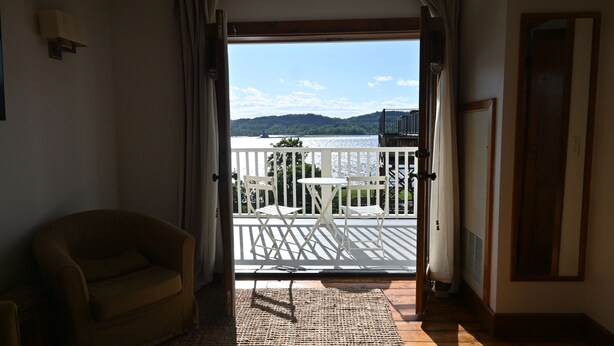 Ein Zimmer mit Seeblick, ein Balkon mit Tisch und Stühlen sowie eine Sitzecke.