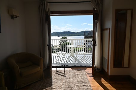 A room with a view of a lake, a balcony with a table and chairs, and a sofa.. Rhinecliff Hotel