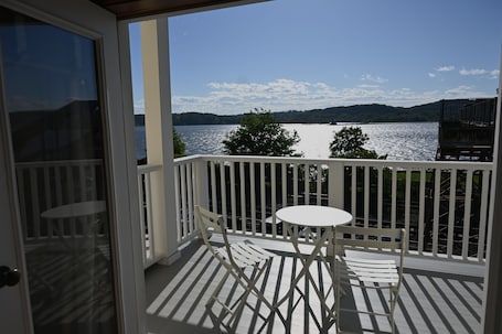 A balcony with a white table and chairs, overlooking a body of water and distant land.. Rhinecliff Hotel