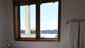 Ein Badezimmer mit freistehender Badewanne, einem Fenster mit Jalousien und einem Handtuchhalter.