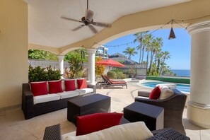 A covered outdoor seating area with wicker furniture, a ceiling fan, and a view of the ocean. - Casa 4 C s in Cabo San Lucas (San José del Cabo)