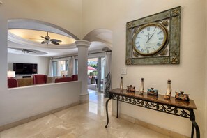 Eine Lobby mit einer großen Wanduhr, einem Empfangstresen und einer Sitzecke mit roten Sesseln.