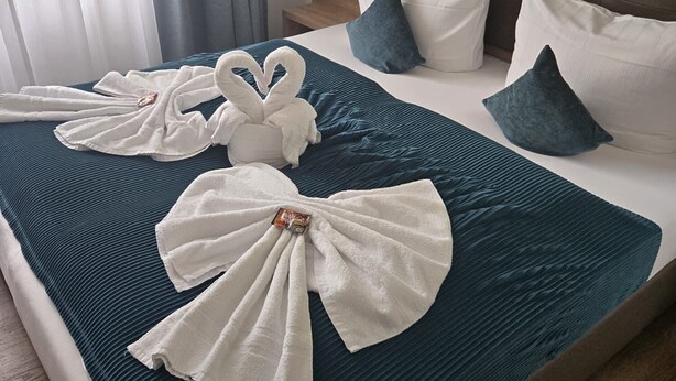 A hotel room with a bed, a nightstand, a lamp, and a window with curtains.