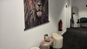 A hallway with a large lion mural, two upholstered chairs, a small table with magazines, and a fire extinguisher. - VILLAWIE  (Rheda-Wiedenbrück)
