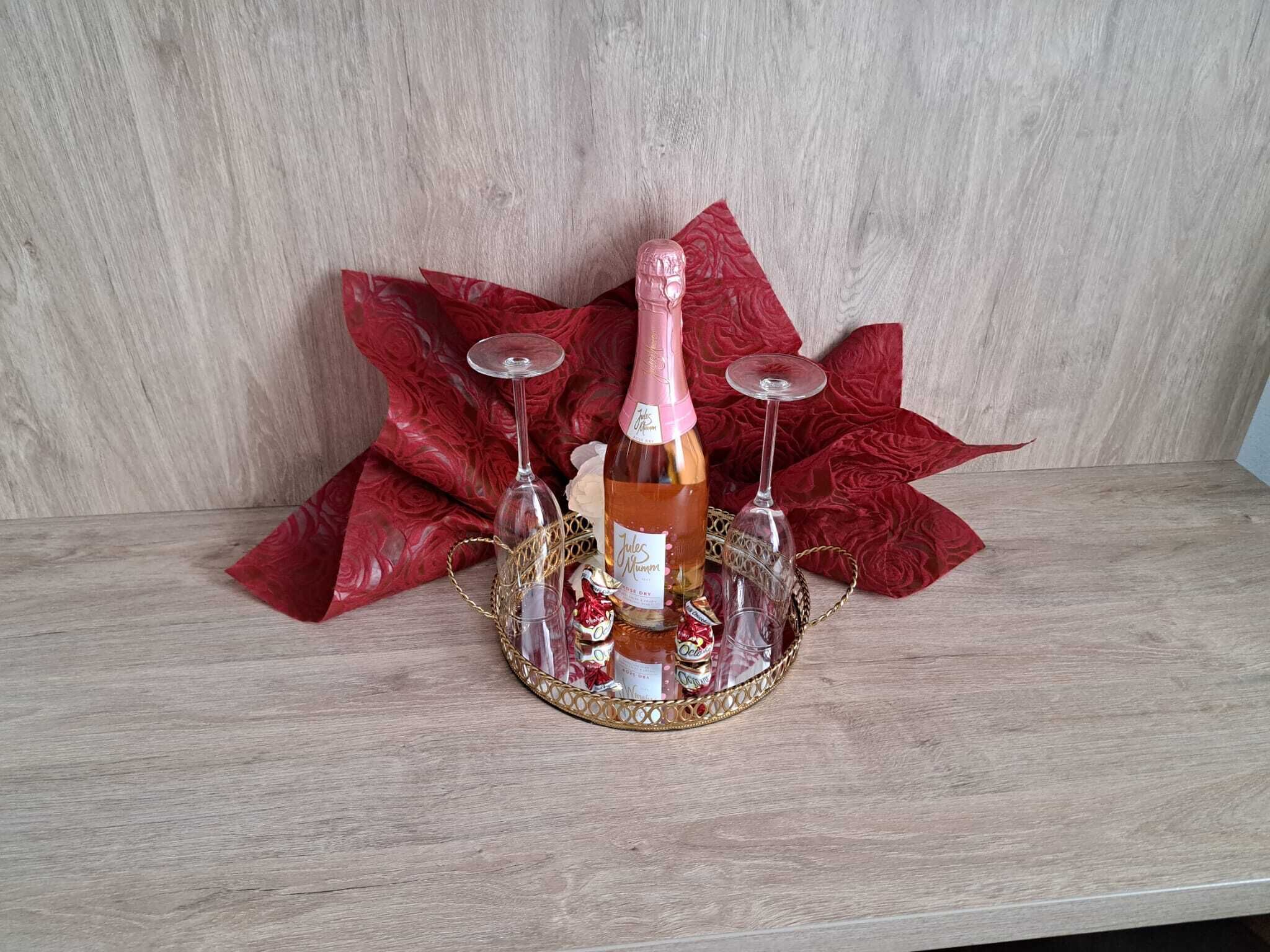A bottle of wine, two glasses, and a decorative tray on a wooden surface.