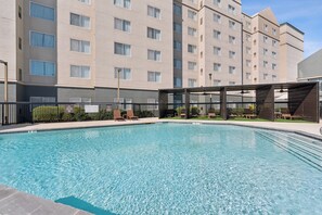 A swimming pool with lounge chairs and a building in the background. -  Elite Dallas Medical District Getaway with Pool View (Dallas)