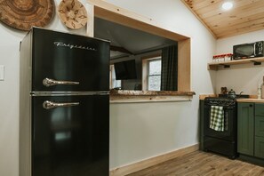 A kitchen with a black refrigerator, a microwave, a stove, and wooden cabinets.