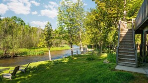 A riverside view with a wooden deck and chairs. - Platte River Sauna, Hot Tub & Kayaks, Near Dunes (Honor)