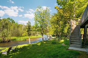Uitzicht op de rivier met een houten terras en stoelen.