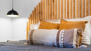 A bed with a wooden headboard, a black pendant light, and multiple pillows. - Platte River Sauna, Hot Tub & Kayaks, Near Dunes (Honor)
