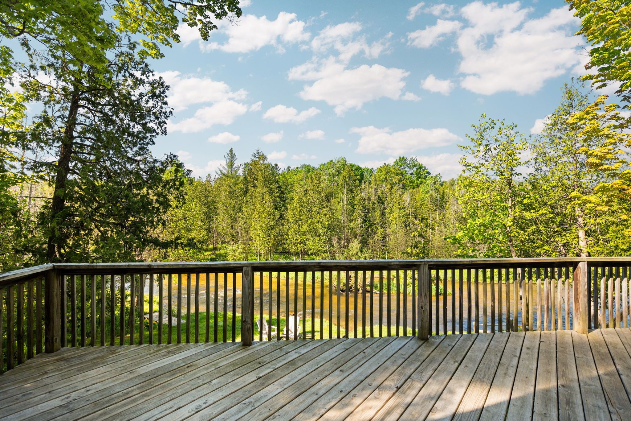 Une terrasse en bois dotée d’une rambarde, qui offre une vue sur une zone boisée.
