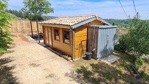 A small wooden cabin with a tiled roof, a wooden door, and a small attached shed. - Charming wooden chalet - Ardèche (Joyeuse)