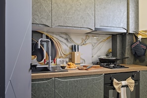 Eine moderne Küche mit Marmor-Spritzschutz, einem Gasherd und einem eingebauten Backofen.