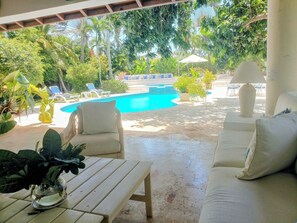 Et poolområde med en hvid sofa, liggestole og et bord med en plante.