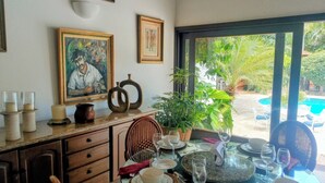 A dining area with a table set for four, a potted plant, and framed artwork on the wall. - Coral Suite at Casa de Campo Resort & Villas Golf Playa (La Romana)