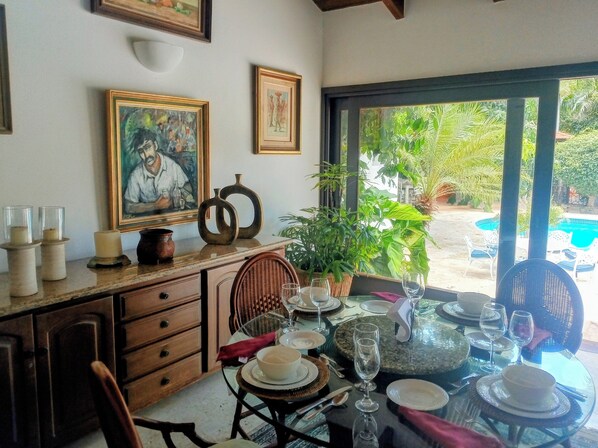 A dining area with a table set for four, a potted plant, and framed artwork on the wall. - Vrbo Property (La Romana)
