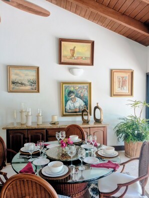 A dining area with a round glass table, wicker chairs, and a wooden ceiling. - Vrbo Property (La Romana)