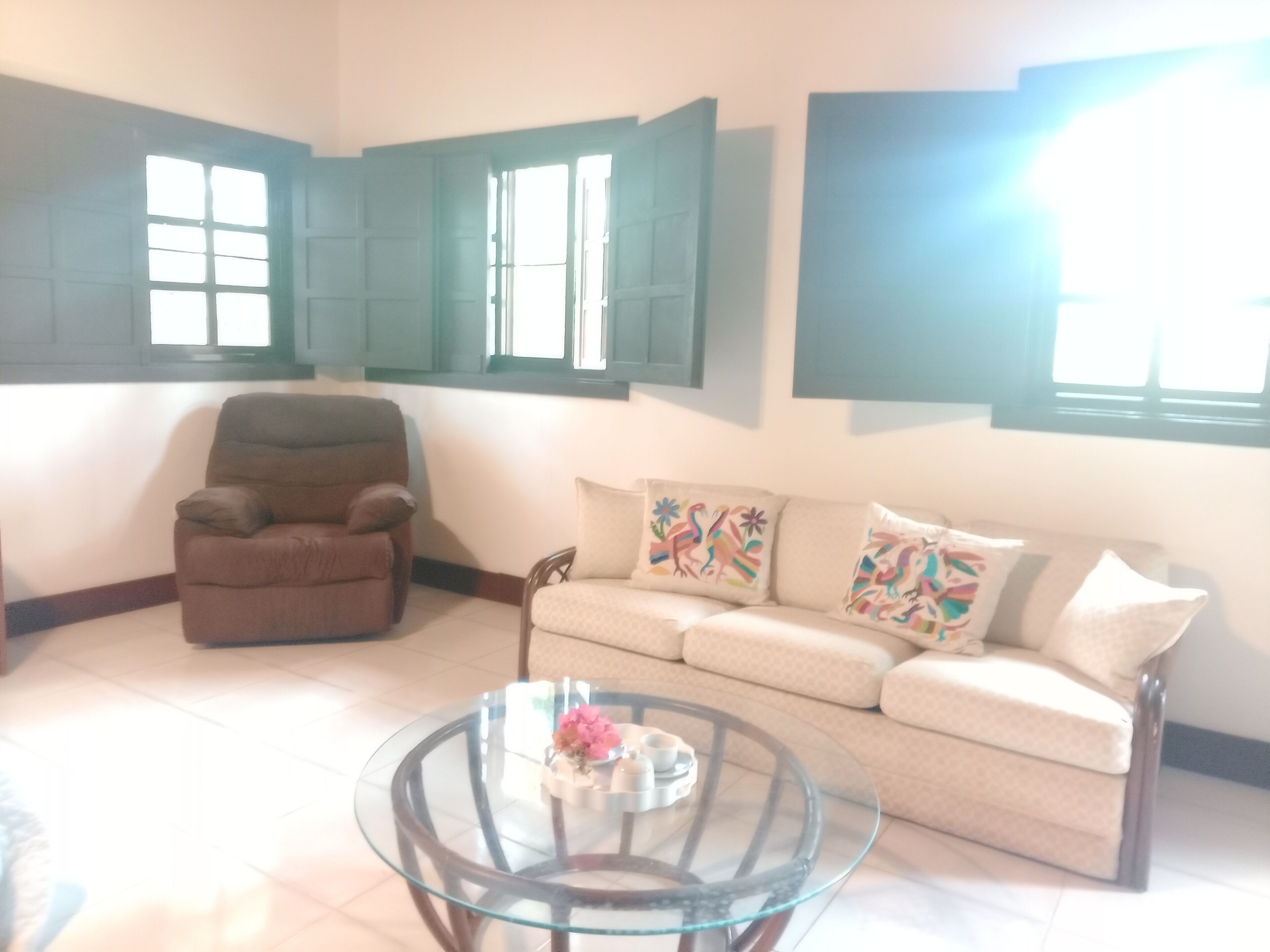 A living room with a sofa, armchair, and glass coffee table.
