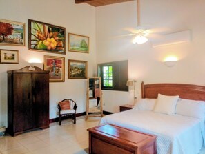 A bedroom with a bed, a wooden nightstand, a chair, a cabinet, and wall-mounted artwork.