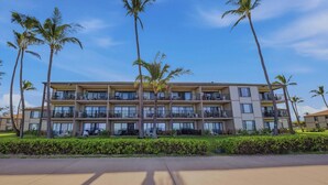 A multi-story hotel with balconies, palm trees, and a well-maintained lawn. - Barefoot Beach Escape Pono Kai Resort  D207 (Kapaʻa)