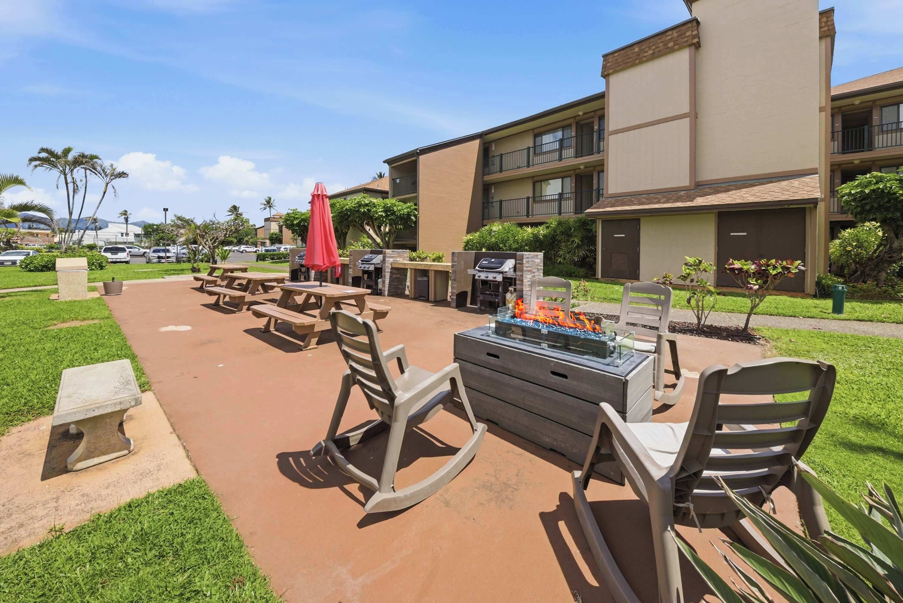 Un espace extérieur aménagé en terrasse, avec des tables de pique-nique, des chaises et un barbecue.
