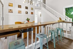 Ein modernes Interieur mit einem Holztisch, Barhocker, einer Treppe und Wandbildern.