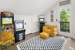 Ein Zimmer mit Spielautomaten, einer Tür, einem Fenster mit Blick und einem gemusterten Teppich.