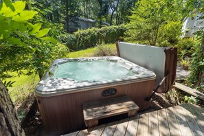 Ein Whirlpool auf einer Holzterrasse, umgeben von viel Grün.