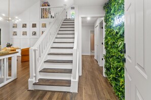 Eine Treppe mit weißen Geländern, Holzstufen und einer Wand mit Grünpflanzen.