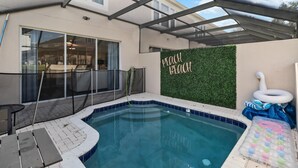 A backyard with a swimming pool, a covered patio, and a wall with 'PEACH BLOOM' written on it. - Gorgeous 3/3 townhome at gated Resort Community at Windsor Palms!! (Kissimmee)