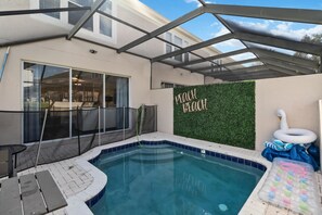 Ein Garten mit Schwimmbad, überdachter Terrasse und Mauer mit der Aufschrift 'PEACH BLOOM'.
