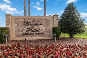 Schild für Windsor Palms, eine bewachte Resort-Gemeinschaft, mit Steinmauer und bepflanztem Bereich mit Blumen.