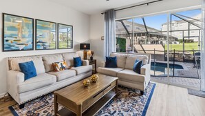 A modern living room with a sofa, coffee table, and artwork on the wall. - Gorgeous 3/3 townhome at gated Resort Community at Windsor Palms!! (Kissimmee)
