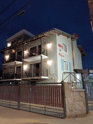 A multi-story hotel with balconies, a stone facade, and a gated entrance.