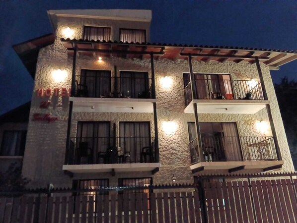 A multi-story hotel with balconies, a stone facade, and a wooden deck.