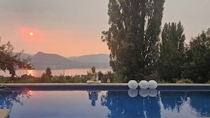 Ett lugnt poolområde med en Buddha-staty, omgivet av träd och med utsikt över bergen.
