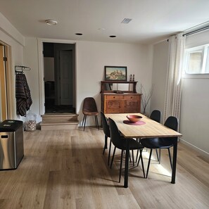 A dining area with a wooden table, black chairs, a wooden cabinet, and a picture above the cabinet. - Naramata Vineyard . Saltwater Pool . Walk to Wineries (Naramata)