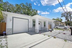 Ein Bungalow mit Garage, überdachter Veranda und Auffahrt.