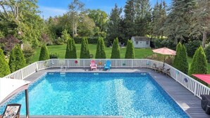 Una piscina rectangular con muelle de madera y barandilla blanca.