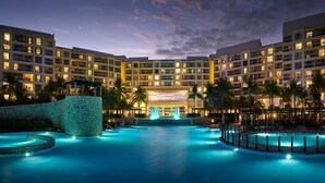 Un hotel con una grande piscina, diversi balconi e palme.