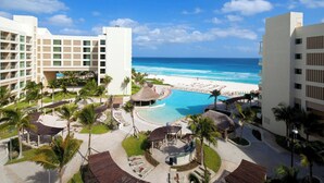 Un resort con piscina, spiaggia e palme.