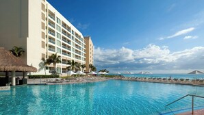 Un hotel con piscina, palme e vista sull'oceano.