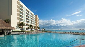 Un hôtel doté d’une piscine, de palmiers et offrant une vue sur l’océan.