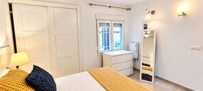 A bedroom with a bed, a bedside table, a wardrobe, a window, and a mirror. - "Fuengirola" "San Francisco Beach" by Accommodation (Fuengirola)