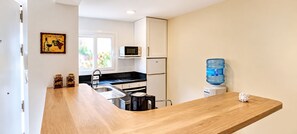 A modern kitchen with a wooden countertop, a sink, a microwave, a refrigerator, and a water dispenser. - "Fuengirola" "San Francisco Beach" by Accommodation (Fuengirola)