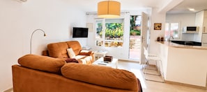 A modern living room with a sofa, a television, and a window with a view of greenery. - "Fuengirola" "San Francisco Beach" by Accommodation (Fuengirola)
