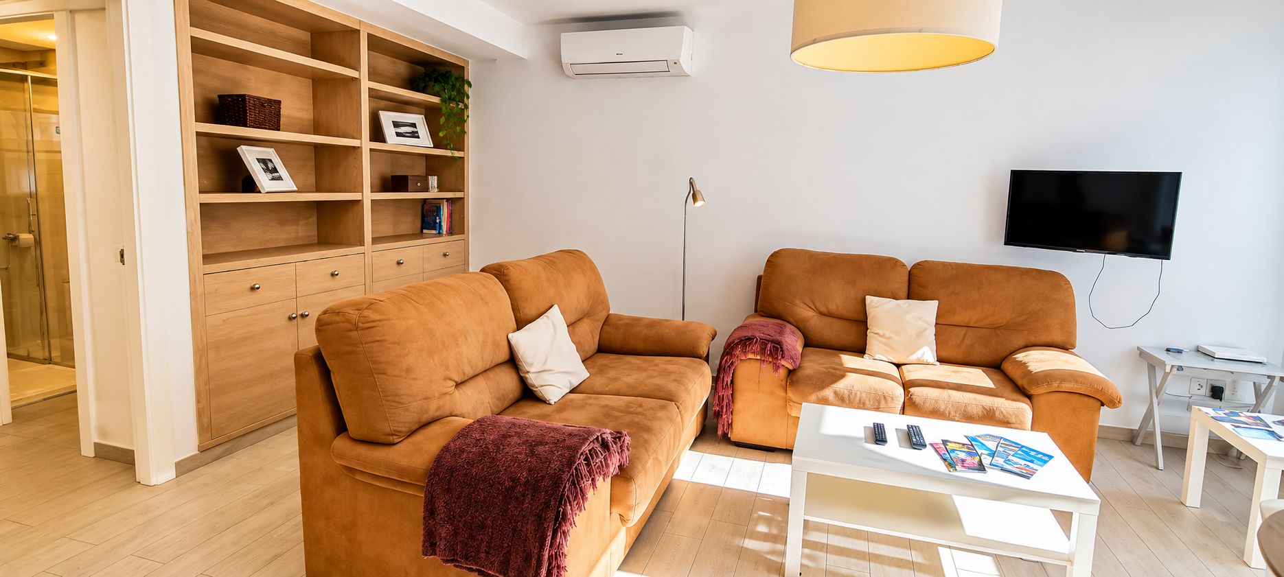 A modern living room with two sofas, a white coffee table, a TV, and a bookshelf.