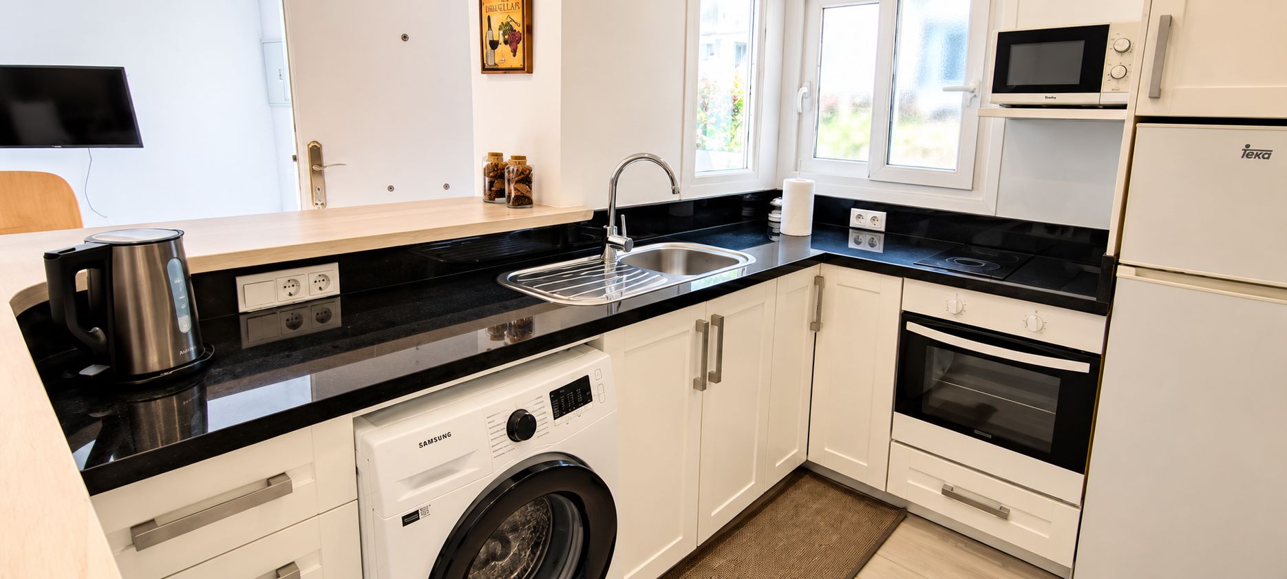 Une cuisine moderne équipée d’un lave-linge, d’un four à micro-ondes, d’un four traditionnel et d’un évier.