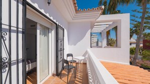 A balcony with a white railing, a small table, and two chairs. - Torremolinos Coliving Playa (Torremolinos)